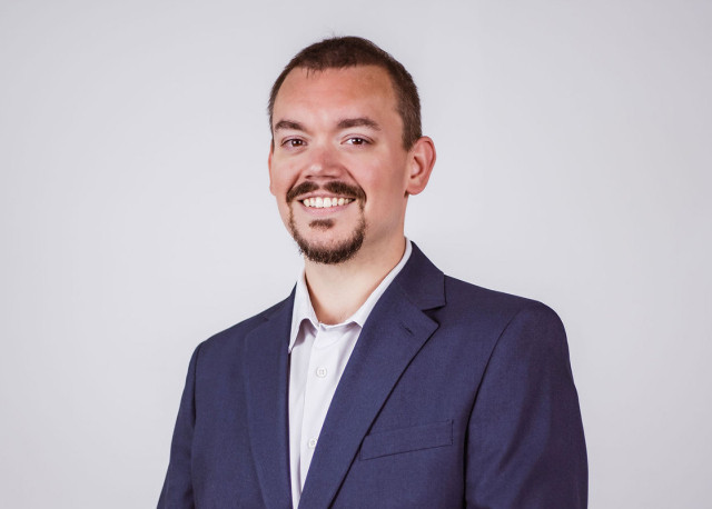 Nathan in a suit coat on a gray background